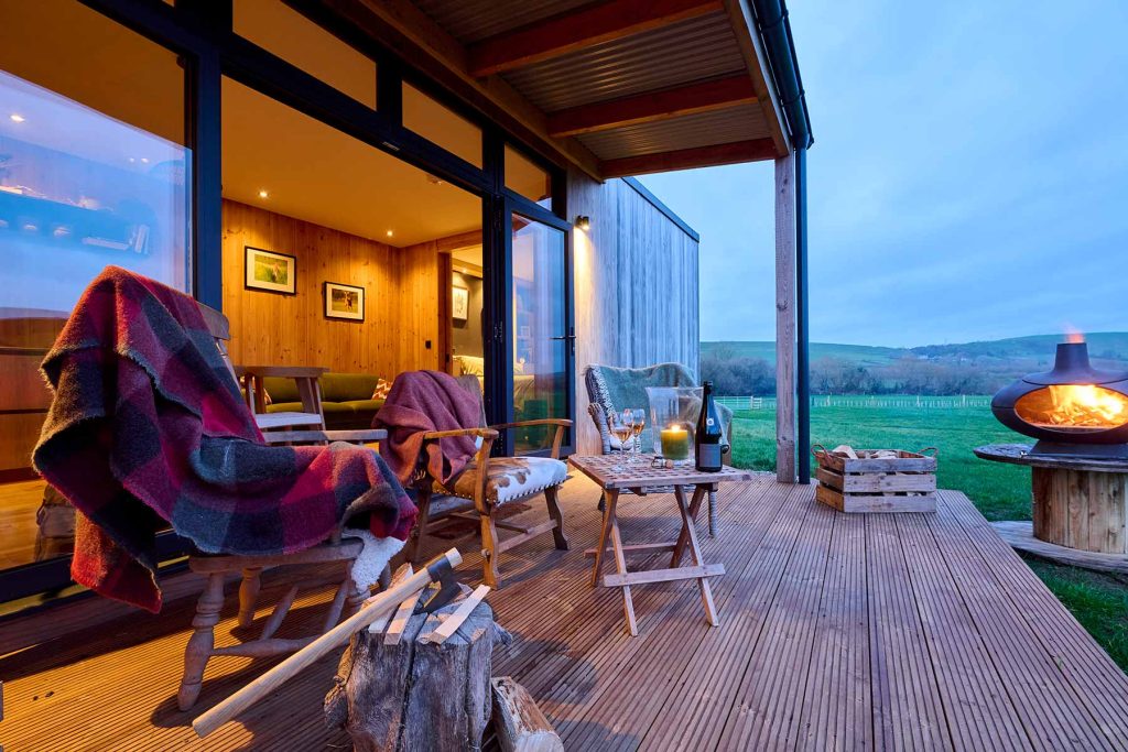 Sunset shot of the cabins veranda, with outdoor seating, wine, and blankets